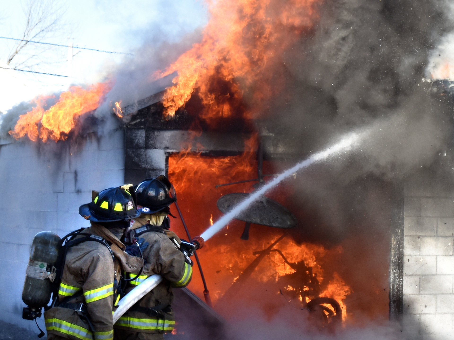 Firefighter battling a large blaze, highlighting fire and smoke cleanup efforts.