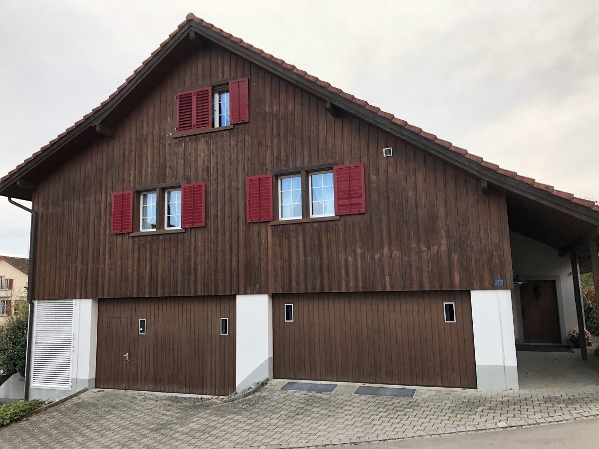 Ein grosses Holzhaus mit roten Fensterläden.