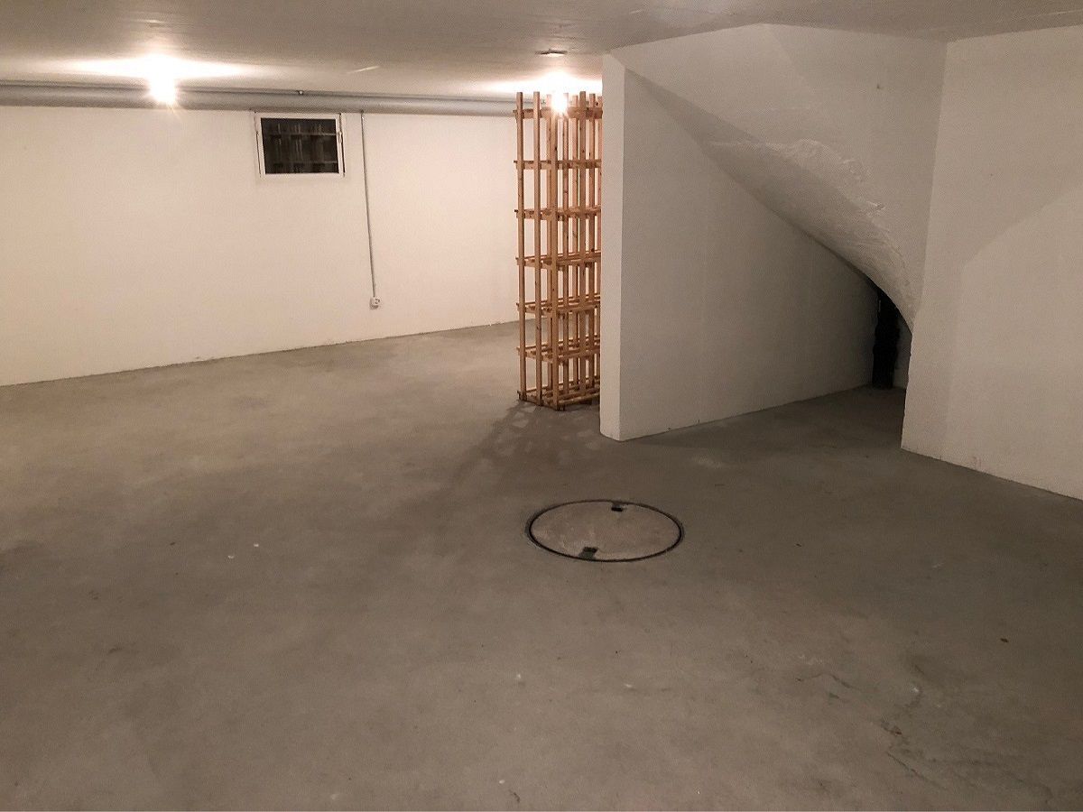 Ein leerer Keller mit Treppe und einem Holzregal