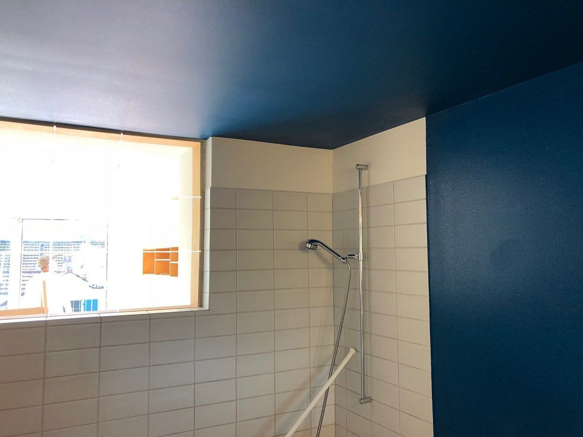 Ein Badezimmer mit blauer Decke und weissen Fliesen