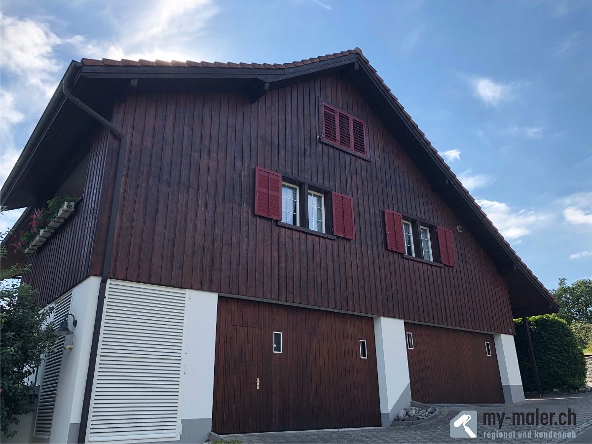 Ein grosses Holzhaus mit roten Fensterläden