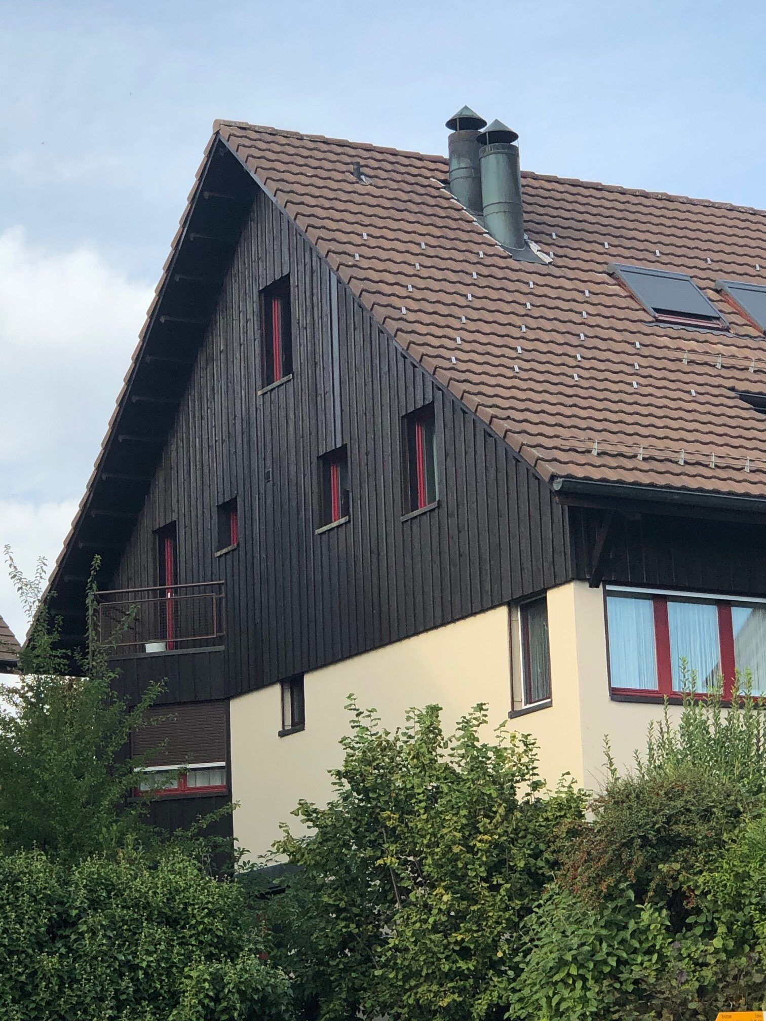 Ein Haus mit einem braunen Dach und ein paar Fenstern