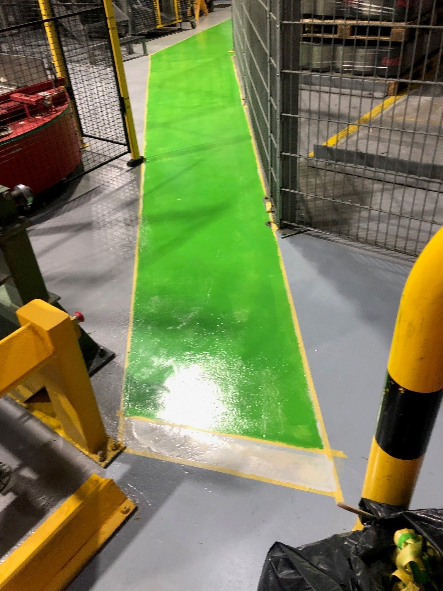 Auf den Boden einer Fabrik ist ein grüner Gehweg gemalt.