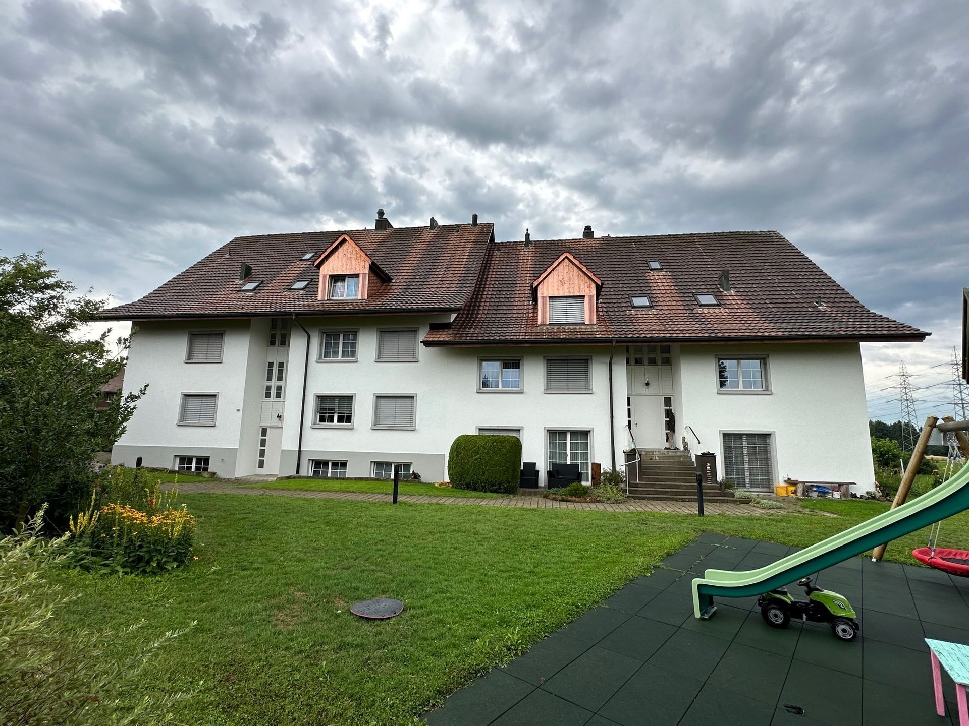 Ein grosses weisses Gebäude mit einem Kupferdach und einem Spielplatz davor.