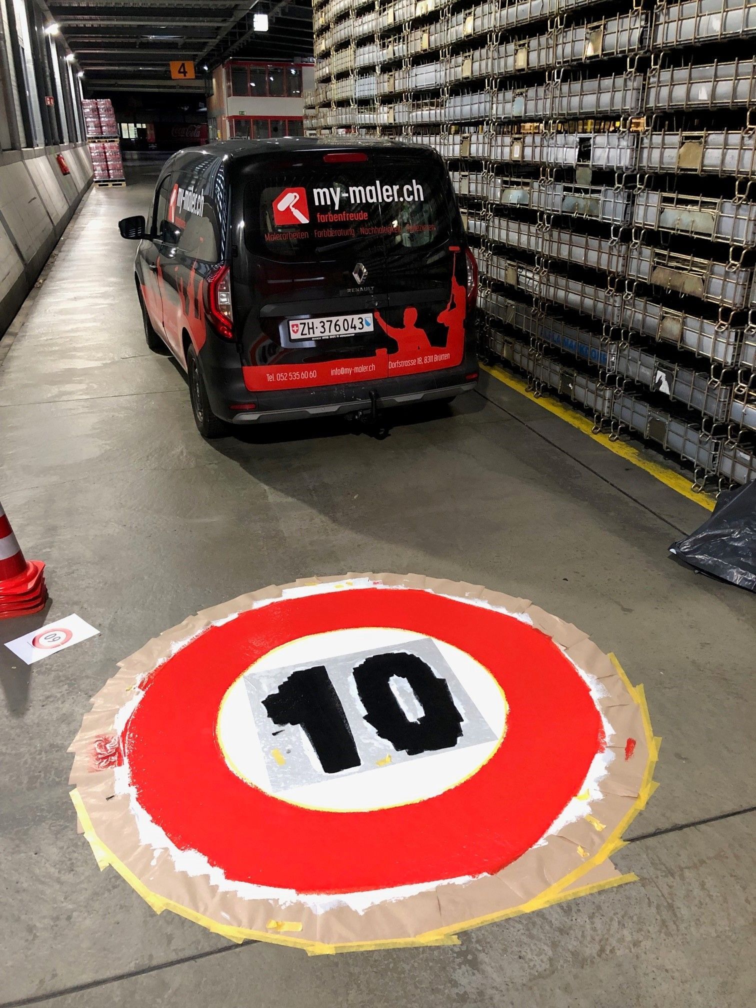 In einer Lagerhalle steht ein Lieferwagen, auf dessen Boden eine Geschwindigkeitsbegrenzung von 10 aufgemalt ist.