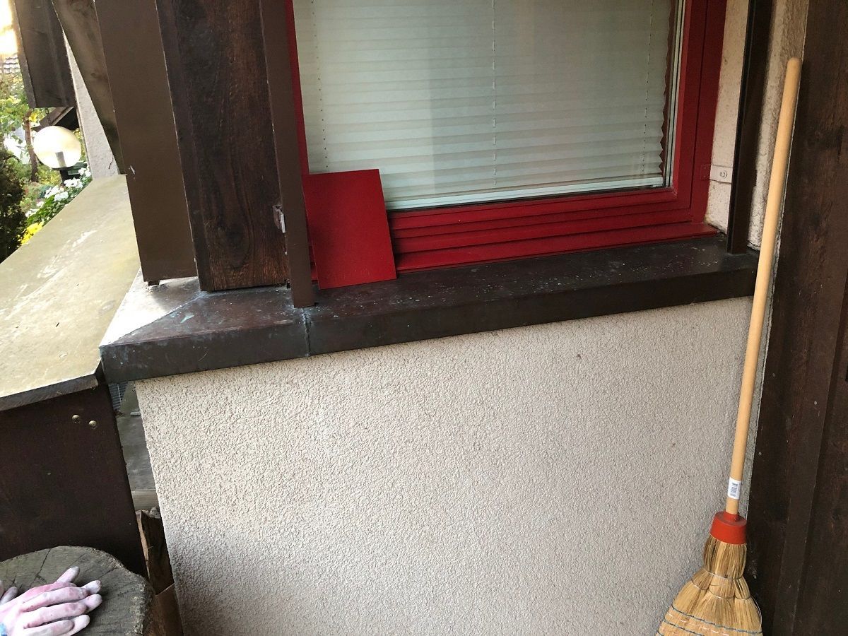 Ein Besen lehnt an einer Wand neben einem Fenster.