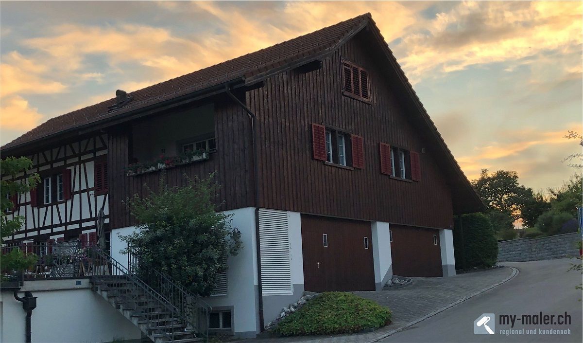 Ein grosses Holzhaus mit einem Sonnenuntergang im Hintergrund.