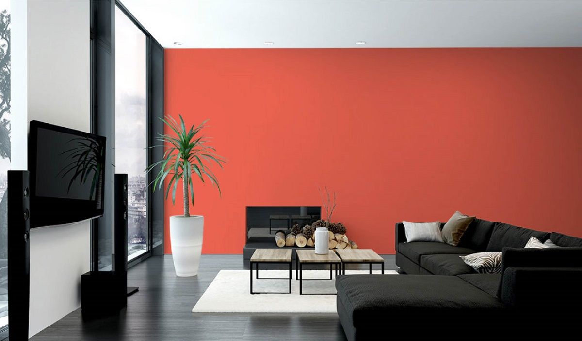 Ein Wohnzimmer mit einer schwarzen Couch und einer roten Wand.
