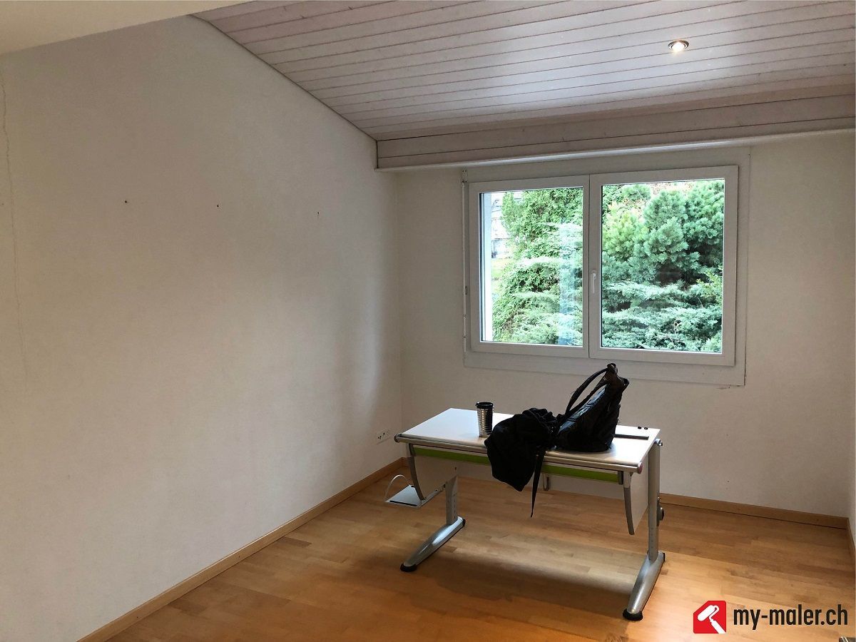 Ein leerer Raum mit einem Schreibtisch und einem grossen Fenster