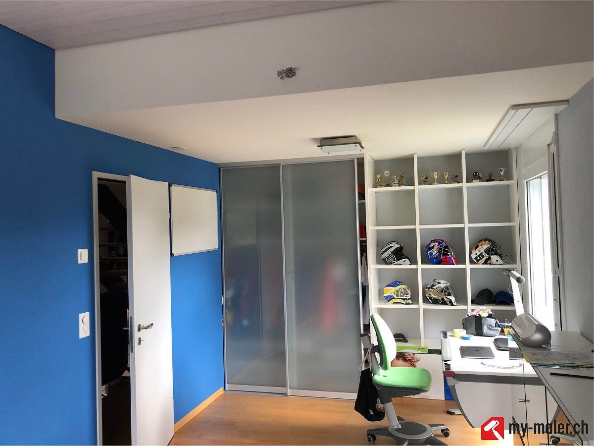 Ein Zimmer mit blauen Wänden und einem Schreibtisch und Stuhl
