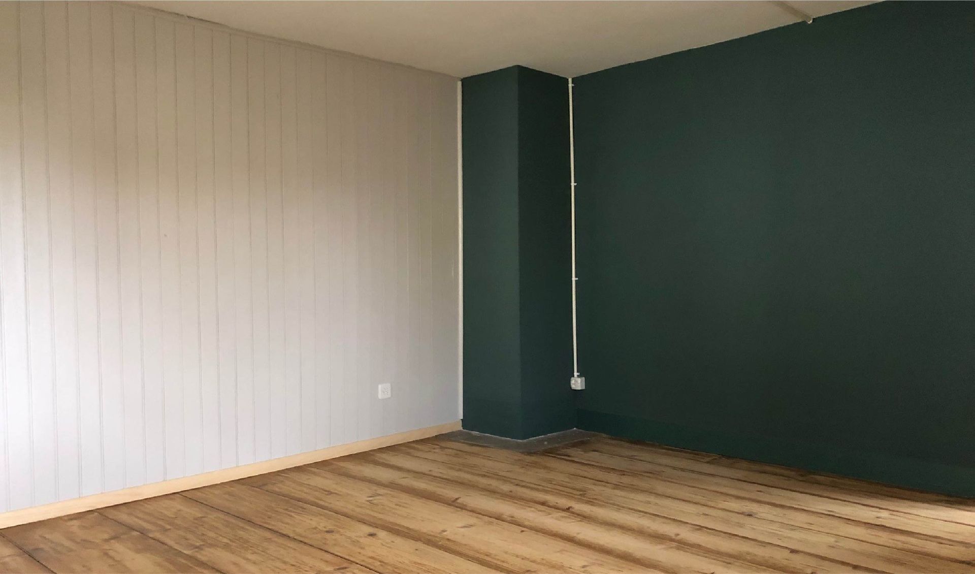Ein leerer Raum mit Holzboden und grüner Wand.