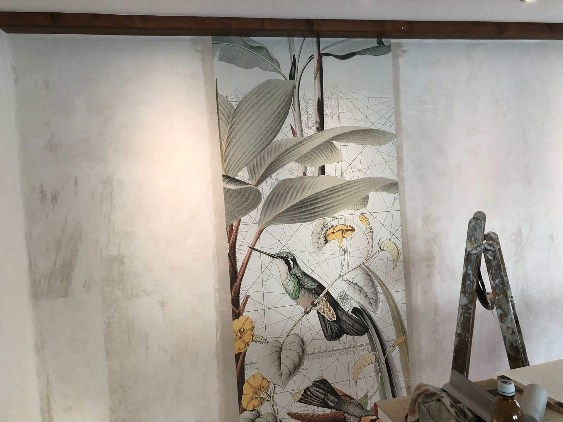 Eine Wand mit einem Bild von einem Kolibri und Blumen darauf.