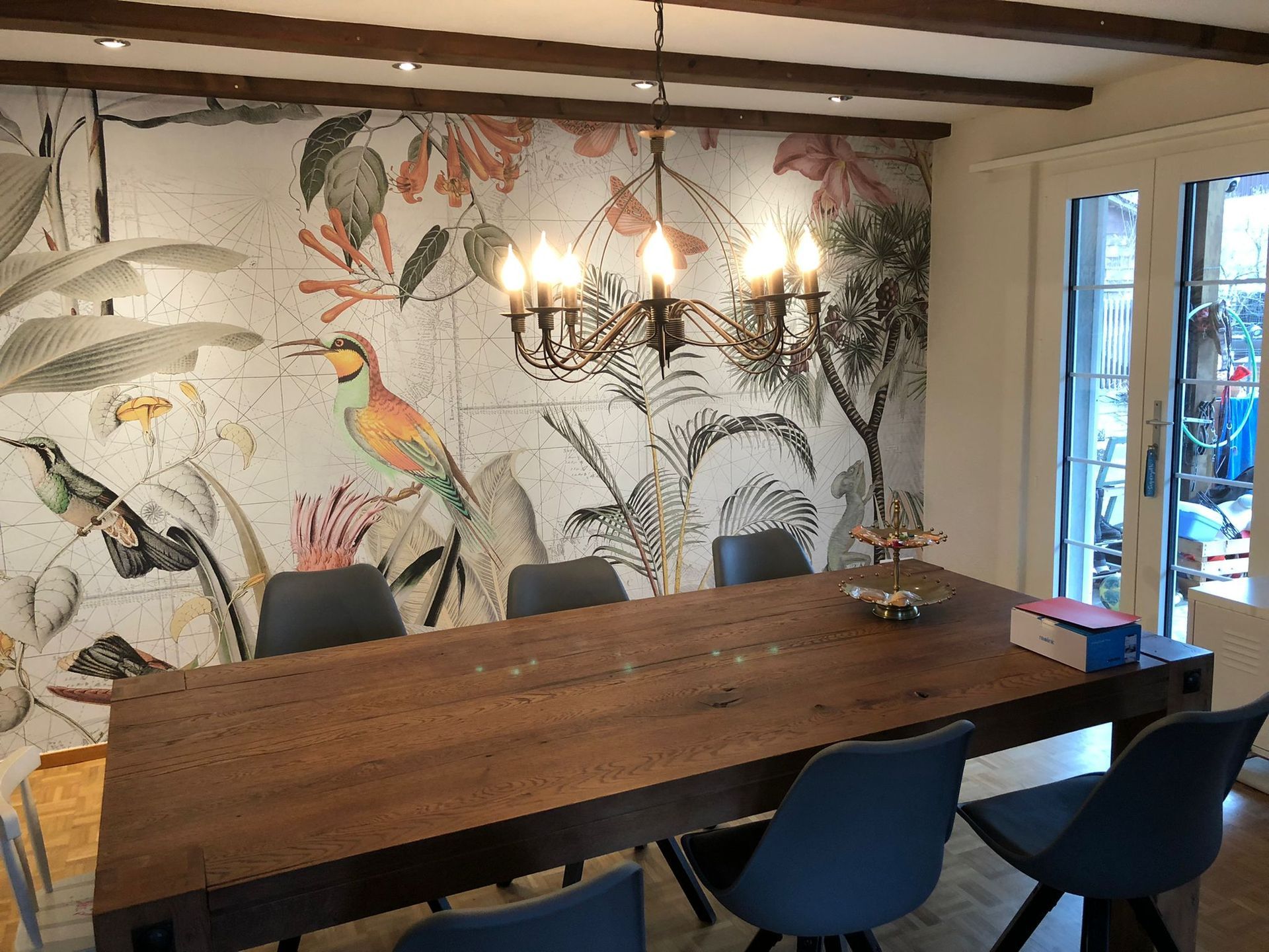 Ein Esszimmer mit einem grossen Holztisch und Stühlen und einem Kronleuchter, der von der Decke hängt.