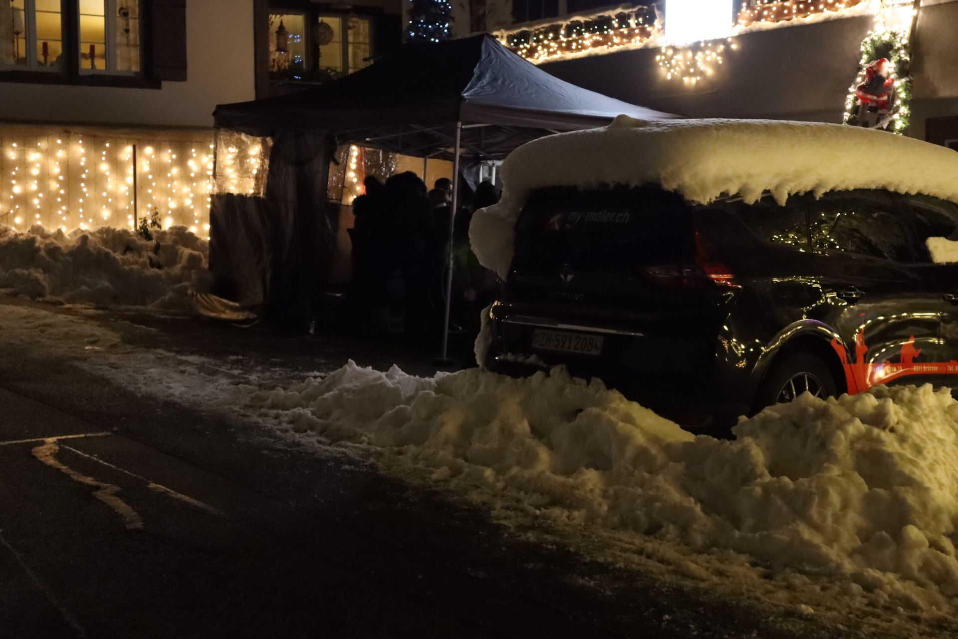 Vor einem Gebäude steht ein schneebedecktes Auto.