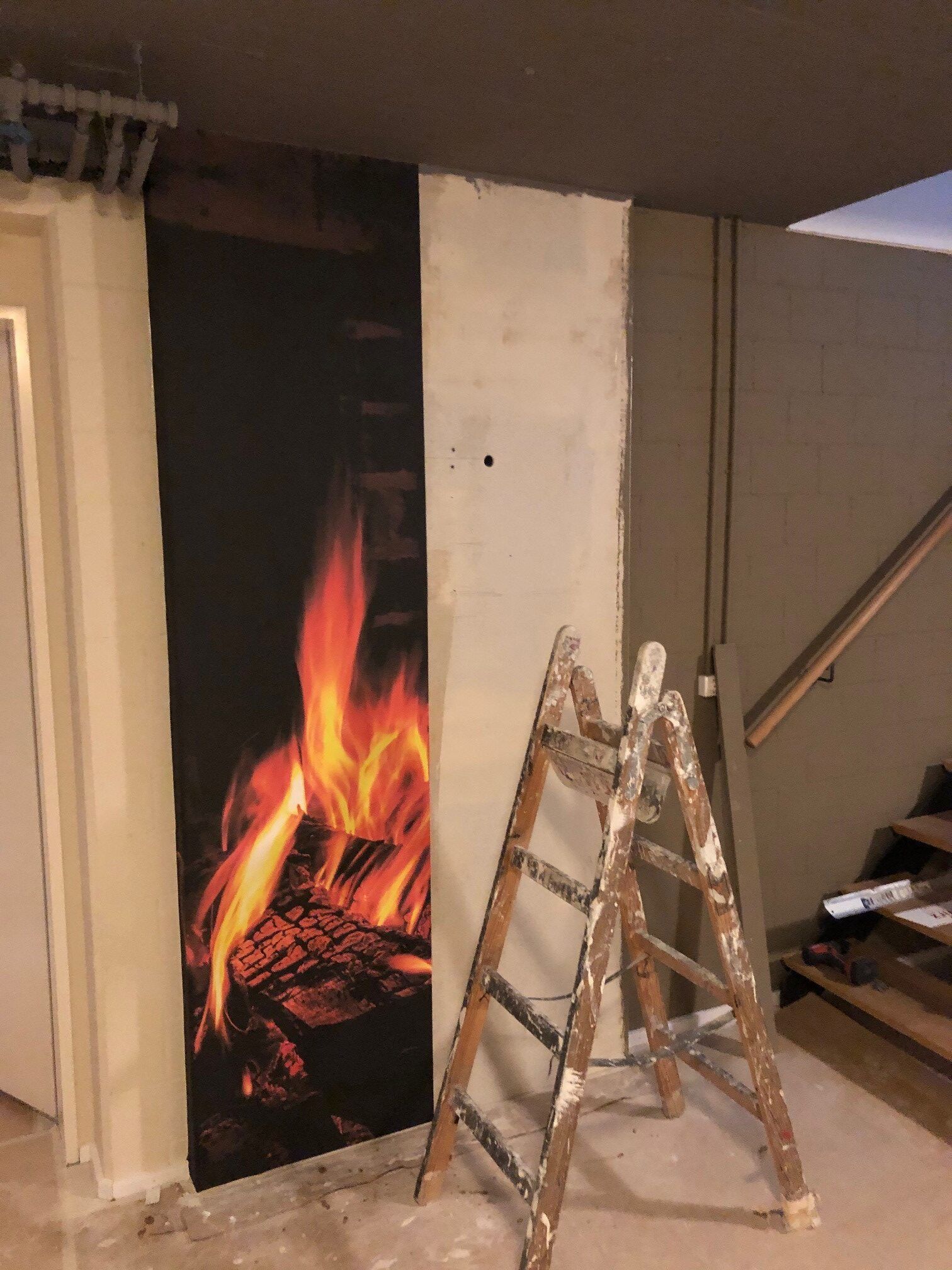 Eine Leiter lehnt an einer Wand mit einem Bild von einem Feuer darauf