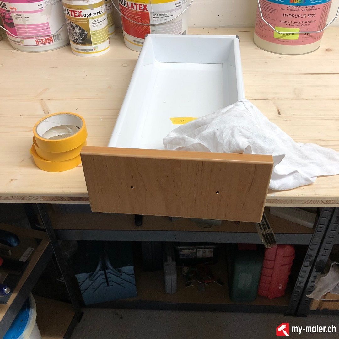Ein Eimer mit Latexfarbe steht auf einem Holztisch