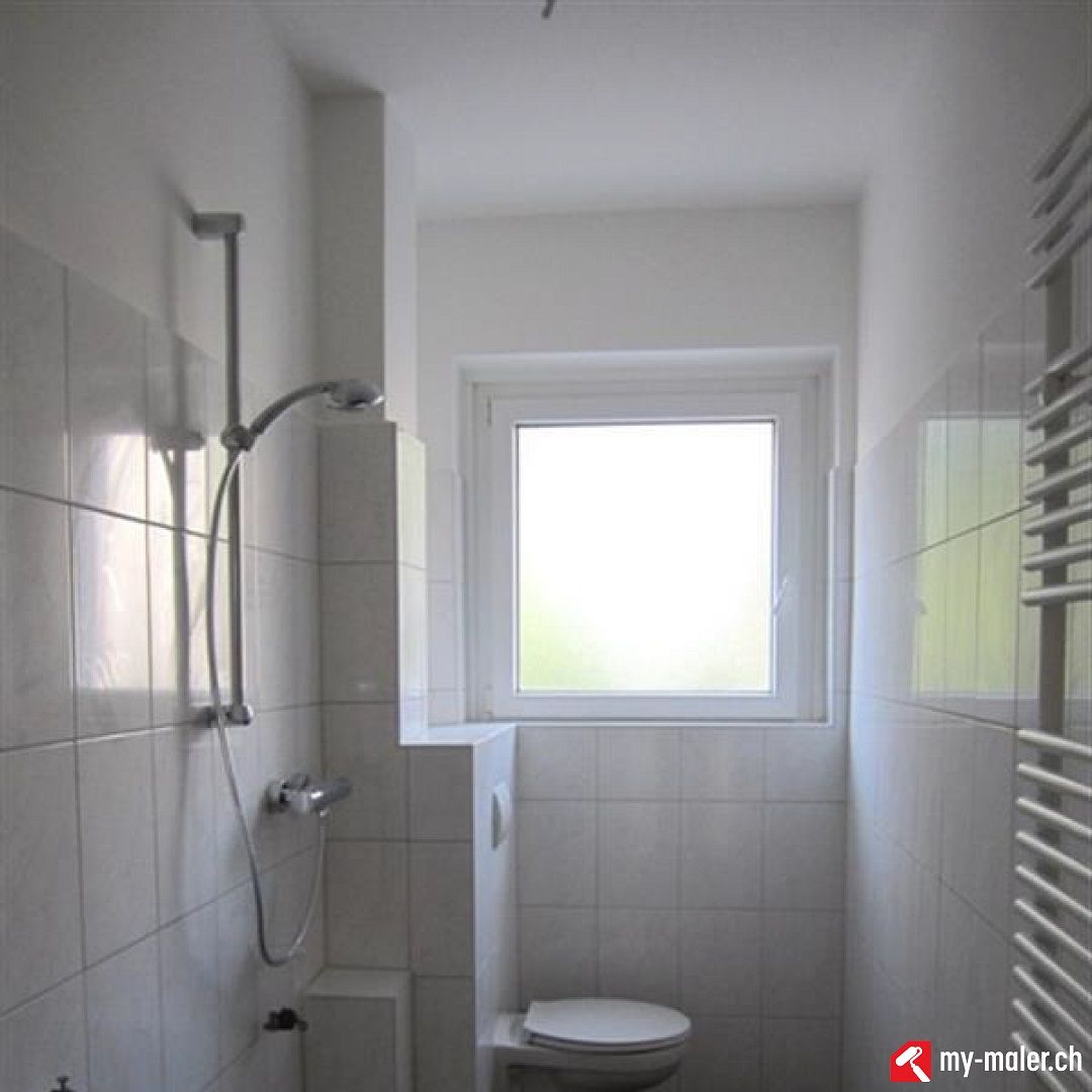 Ein Badezimmer mit Toilette, Dusche und Fenster