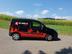 Ein schwarz - roter Lieferwagen steht am Strassenrand.