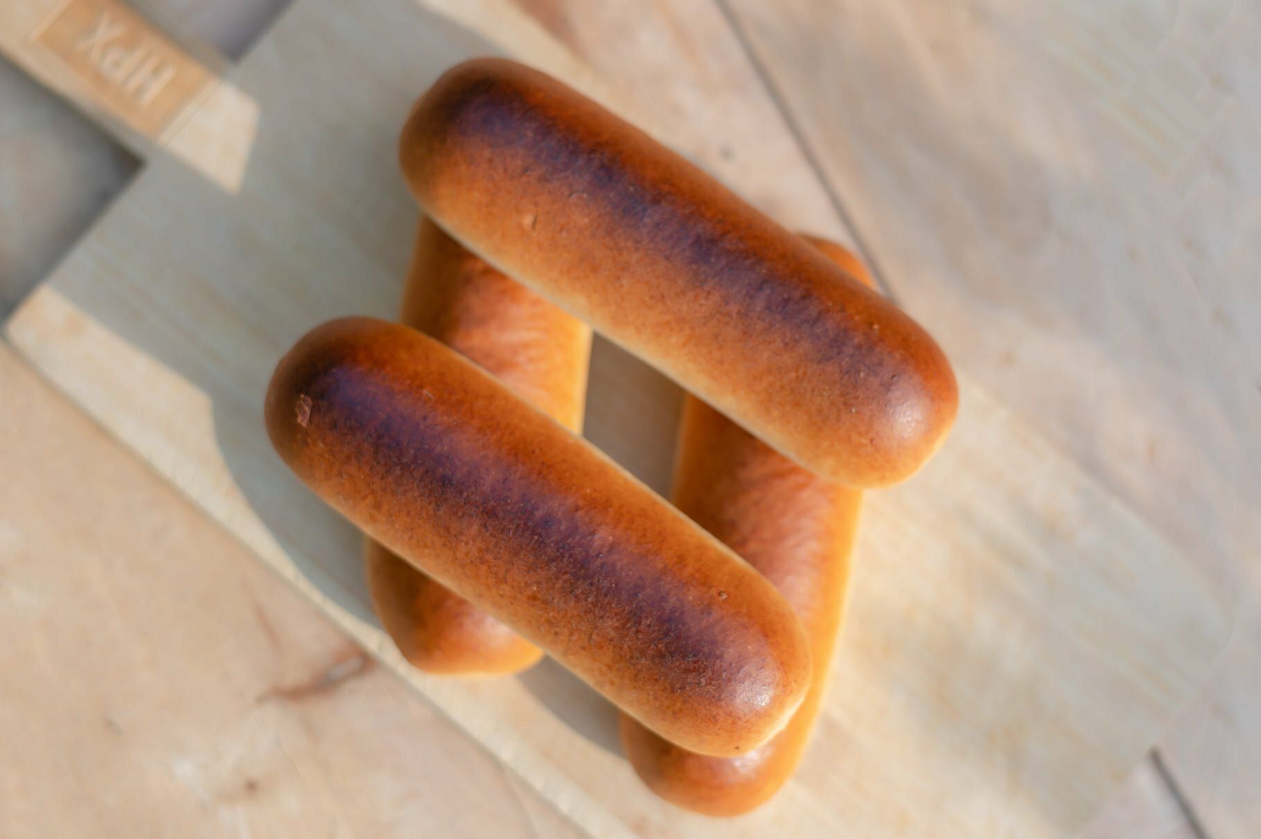 Vier langwerpige, goudbruine broodjes op een houten snijplank, van bovenaf gezien.
