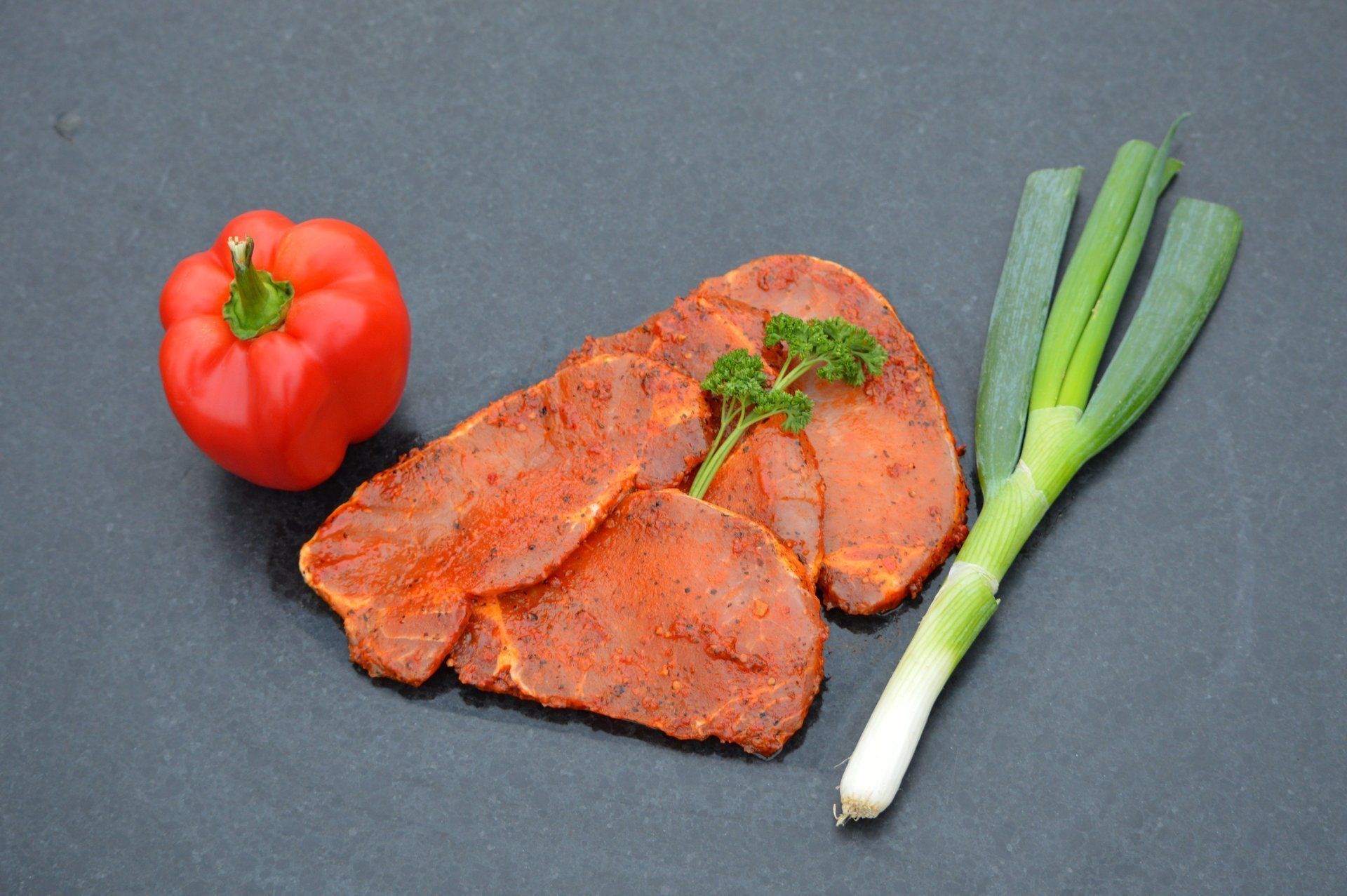 Gekruide vleesplakjes met rode paprika en bosuitjes.