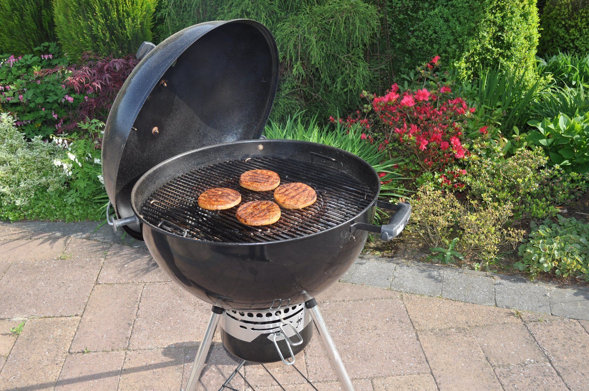 Zwarte houtskoolgrill met hamburgers die buiten worden bereid.