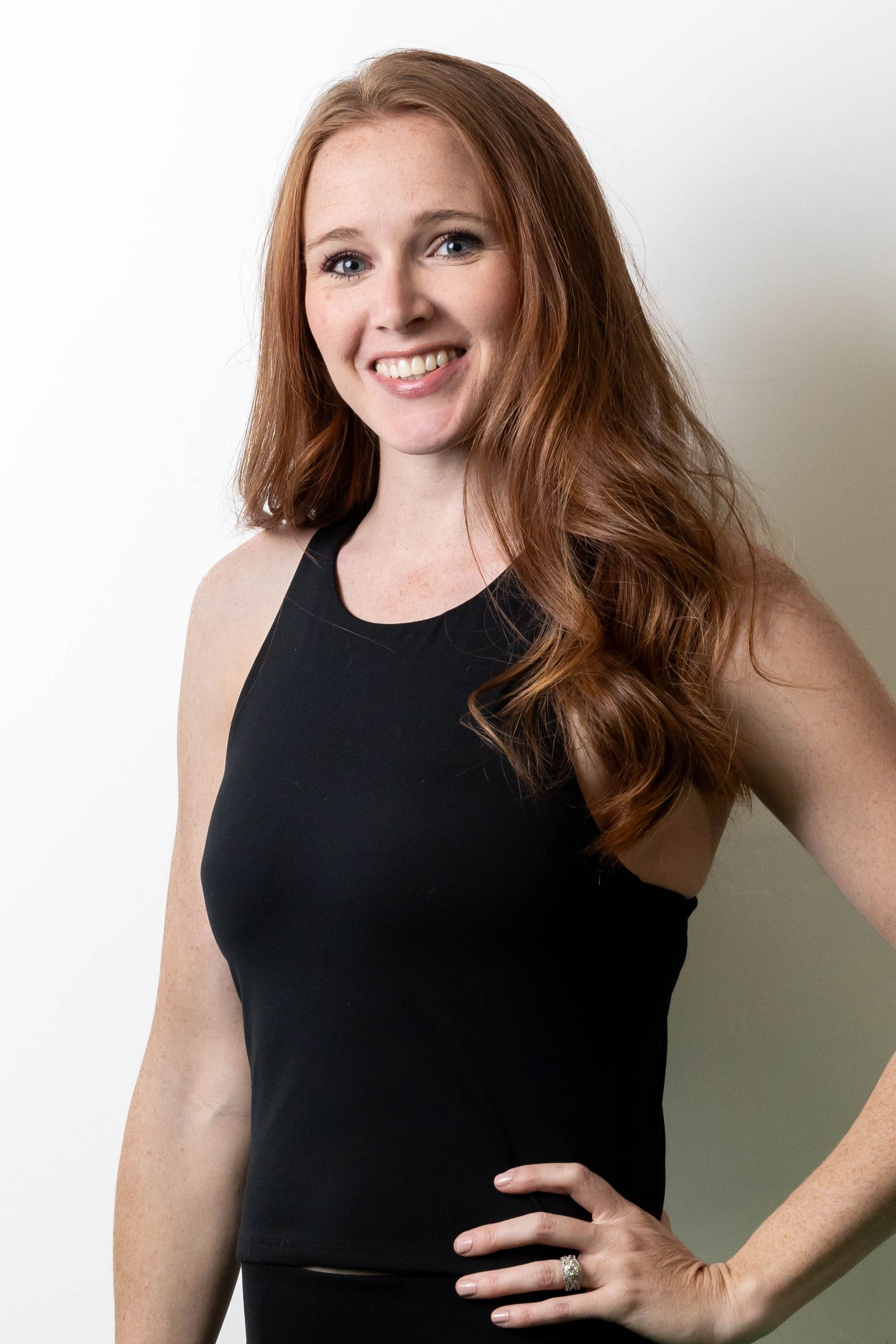 A woman wearing glasses and a black tank top is smiling.