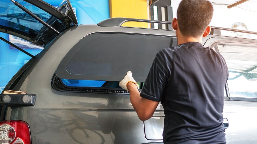 A Man Is Installing A Window Tint On A Car — Advanced Windscreens & Service Centre In Cannonvale, QLD