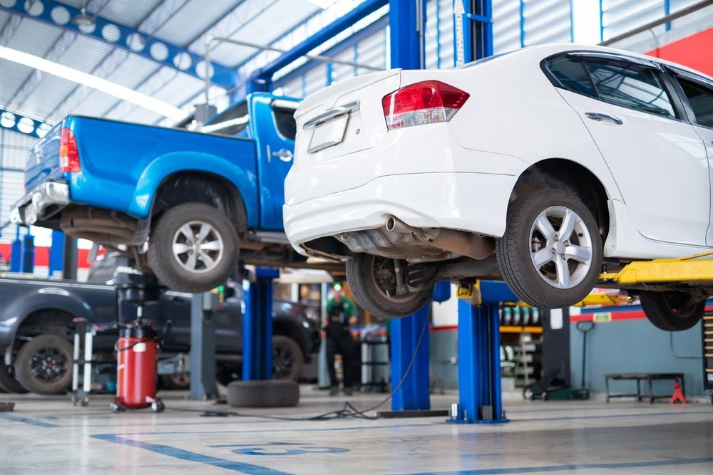 Two Cars Are Sitting On A Lift In A Garage — Advanced Windscreens & Service Centre In Proserpine, QLD