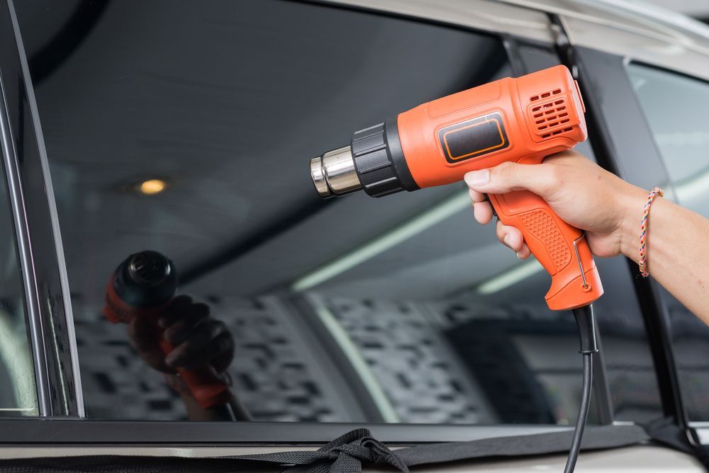 An Orange Heat Gun Used To Smooth A Tint On A Car Window — Advanced Windscreens & Service Centre In Whitsunday Region, QLD