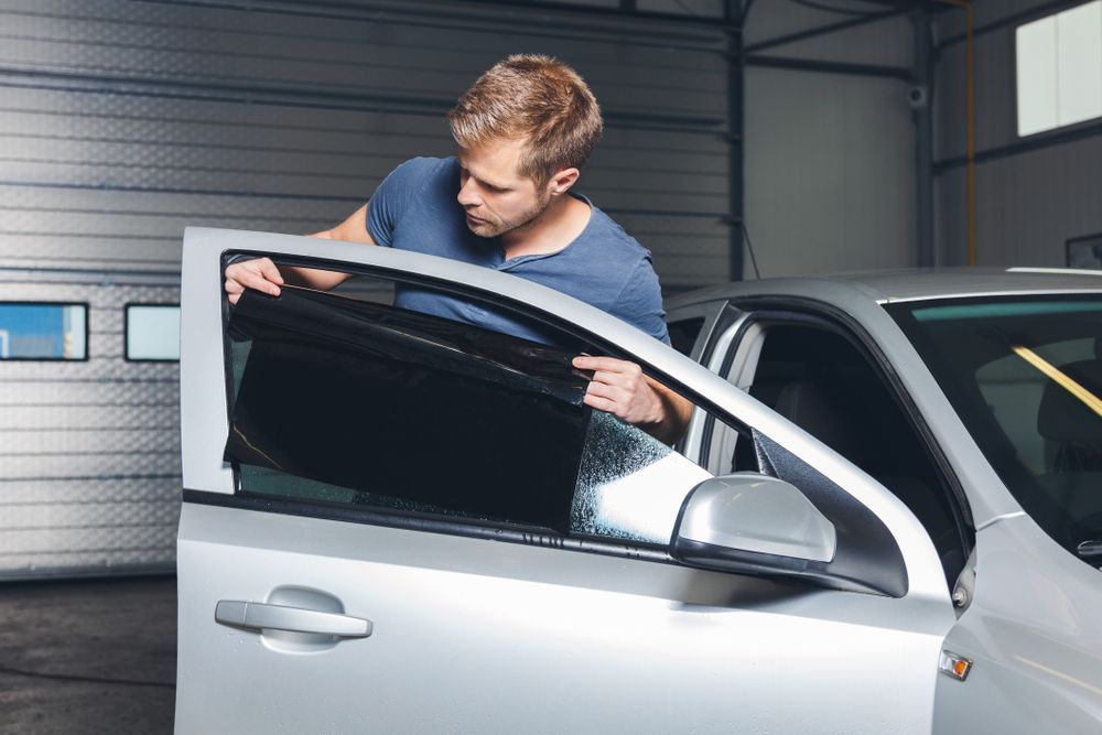 A Man Is Applying Tinted Glass To A Car Window — Advanced Windscreens & Service Centre In Proserpine, QLD