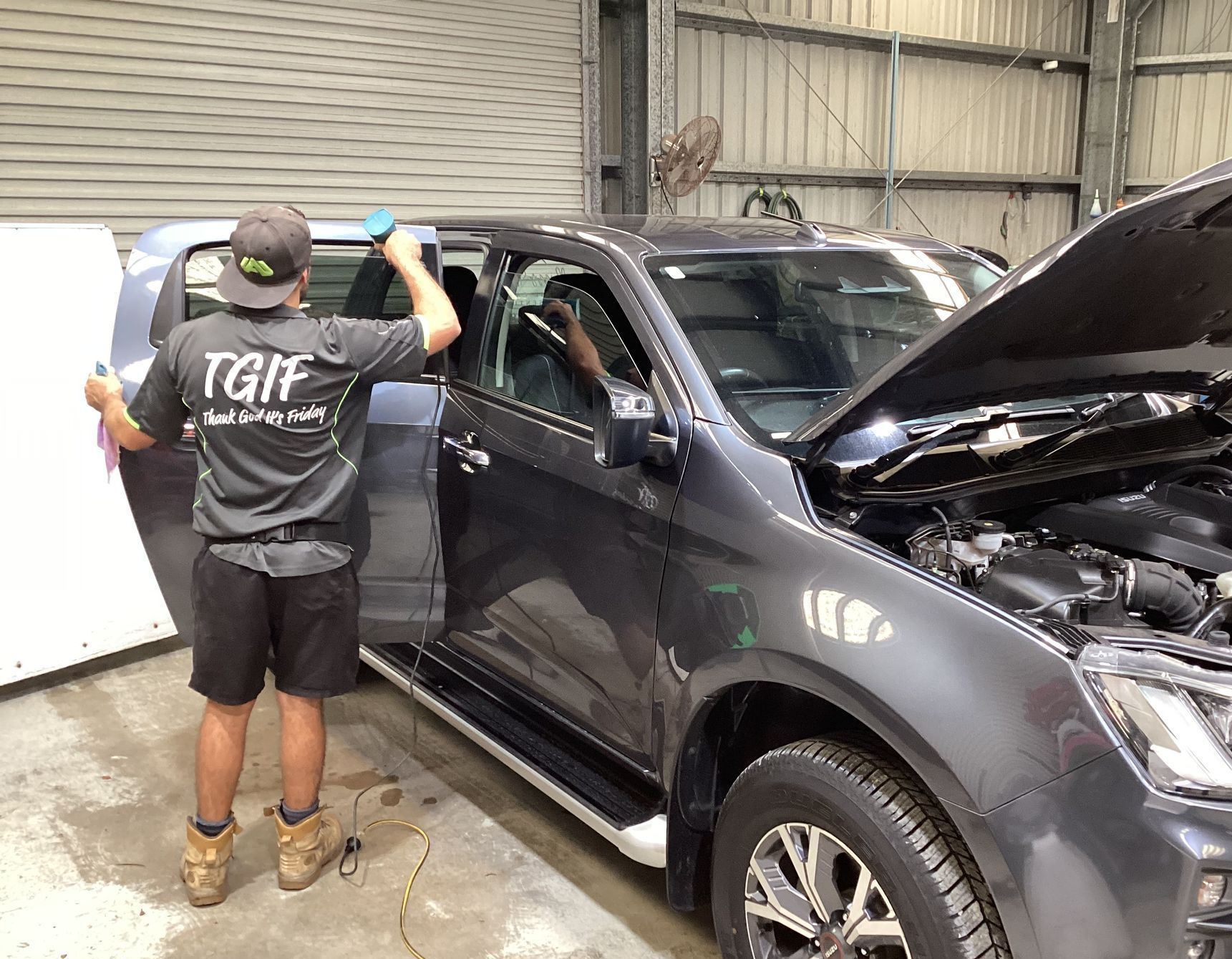 A Man Is Applying Tinted Window Film To A Car Window — Advanced Windscreens & Service Centre In Proserpine, QLD