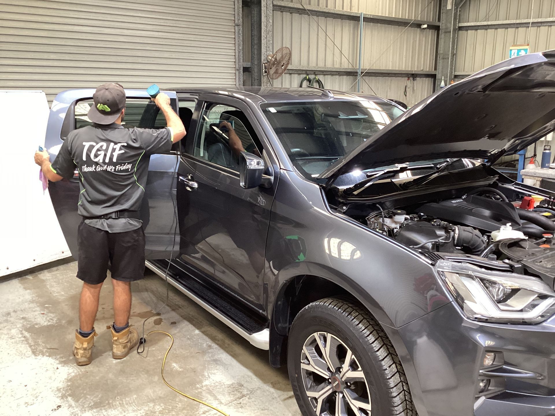 A Man Is Applying Tinted Window Film To A Car Window — Advanced Windscreens & Service Centre In Whitsunday Region, QLD
