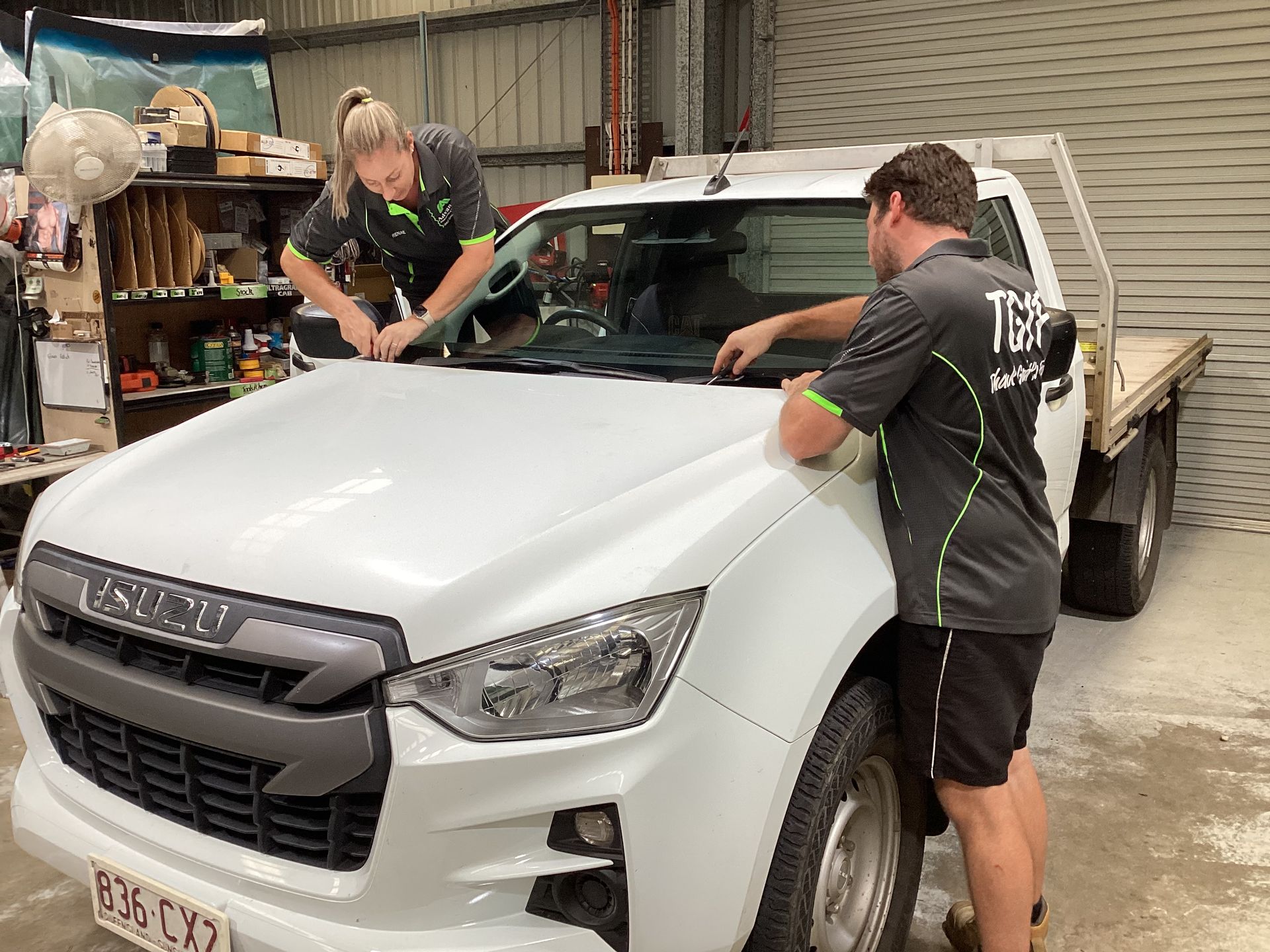 A Woman And A Man Are Replacing A Windscreen On A Car In A Garage — Advanced Windscreens & Service Centre In Proserpine, QLD