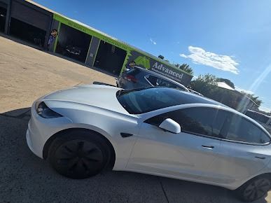 A White Tesla Model 3 Is Parked In Front Of A Building — Advanced Windscreens & Service Centre In Proserpine, QLD