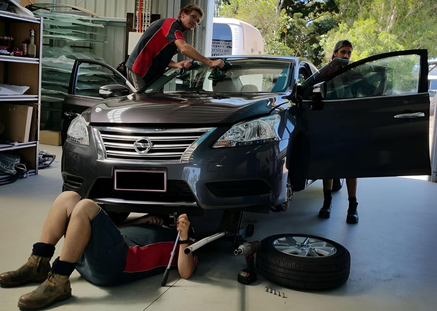 A Group Of People Are Working On A Car In A Garage — Advanced Windscreens & Service Centre In Cannonvale, QLD