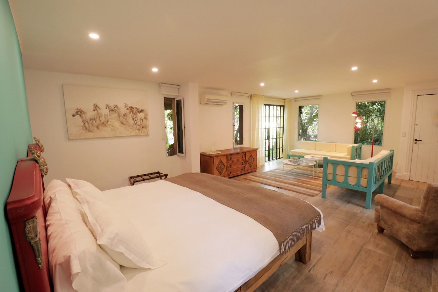 Bedroom with bed, seating area, and wooden chest in a bright, modern space.