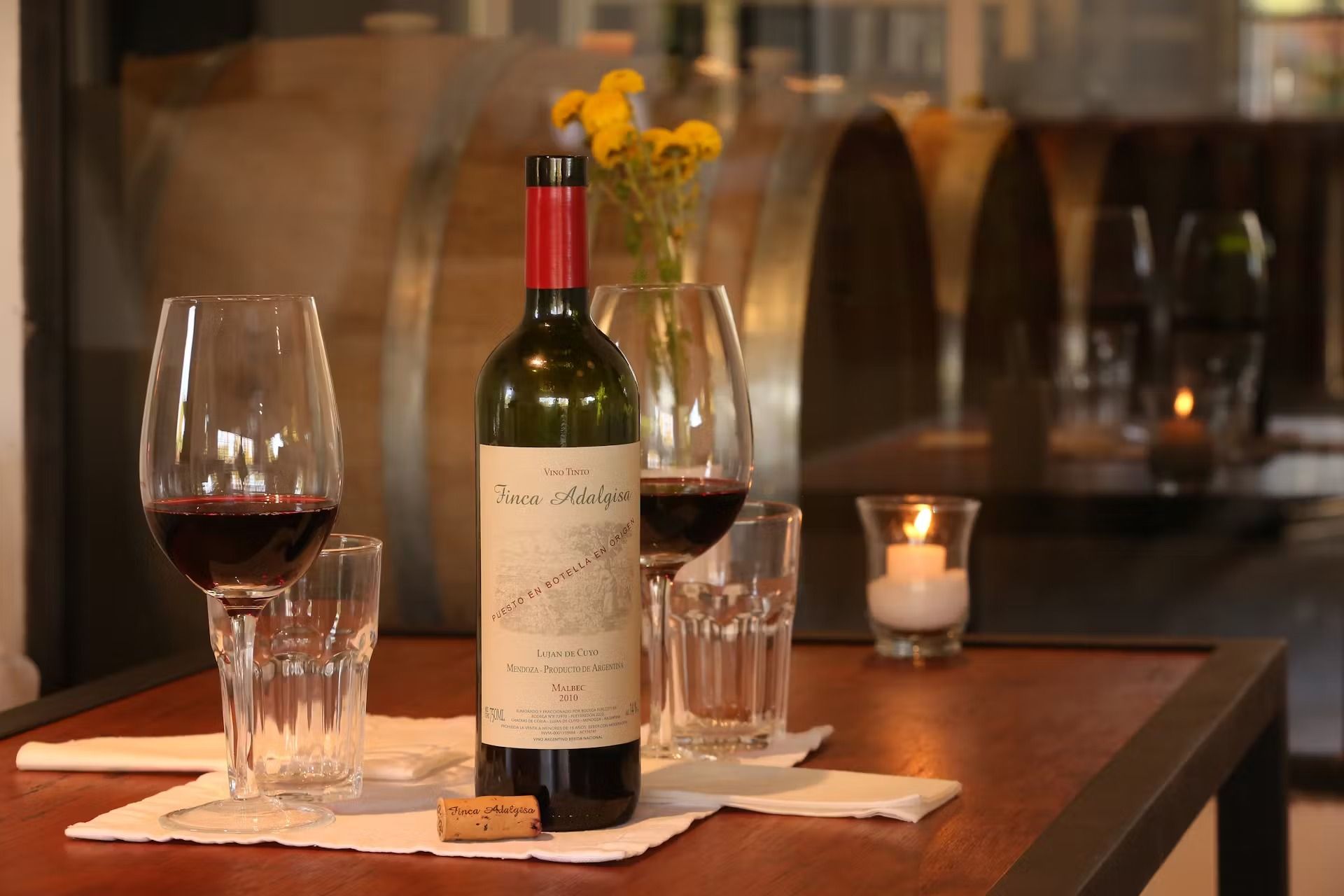 Wine bottle and glasses on a table with a barrel background.