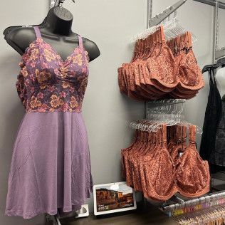 Lace-trimmed lavender dress on a mannequin beside hanging peach lingerie sets in a store display