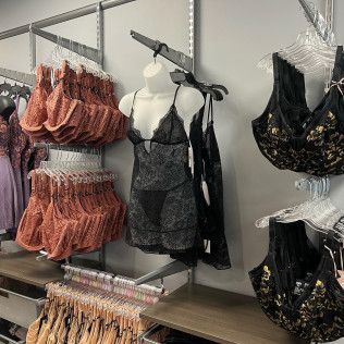 Lingerie display with black and coral bras and panties on racks and mannequins in a store