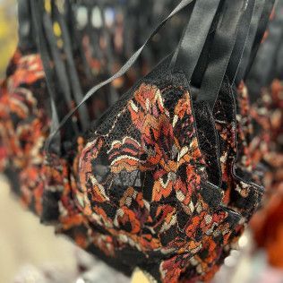 Close-up of a black lace bra with red, orange, and white floral embroidery