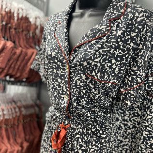 Black-and-white patterned dress with red trim and a red bow belt on a store mannequin