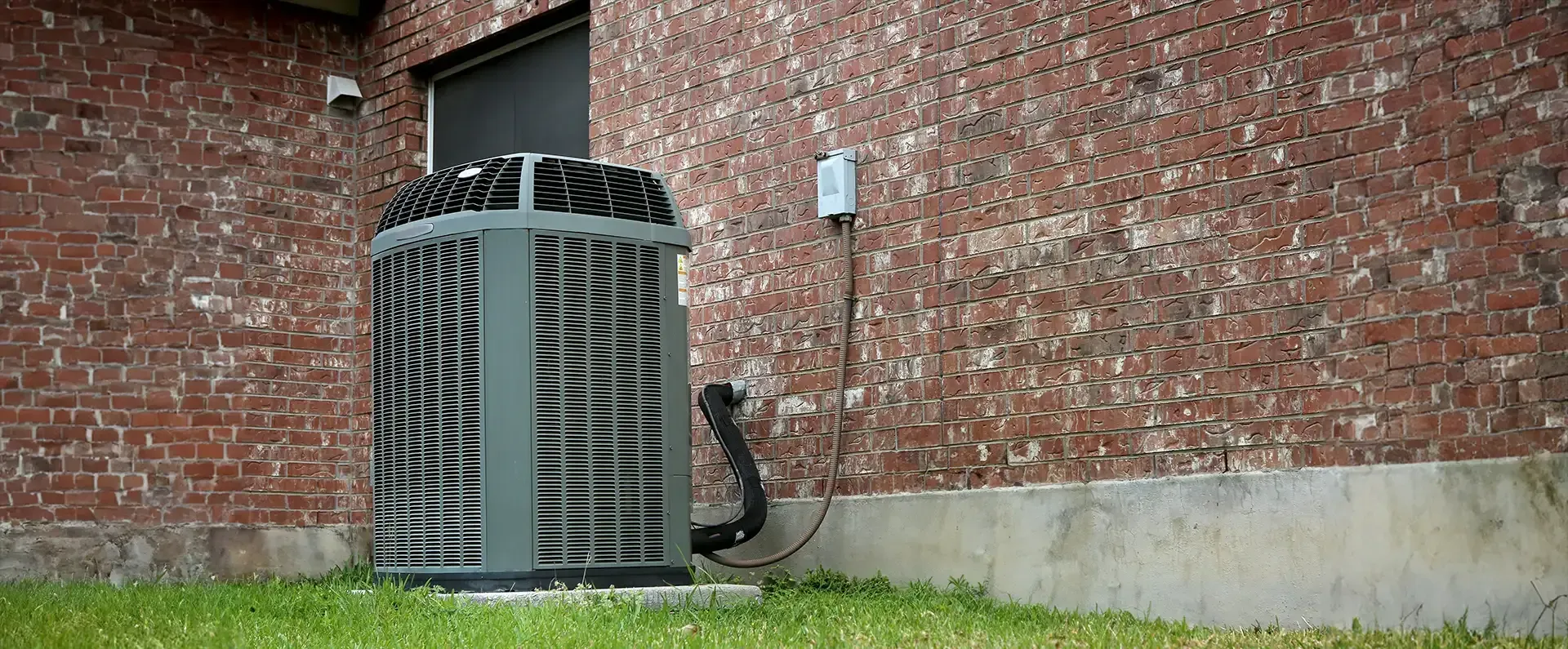 An air conditioning unit next to a brick building.