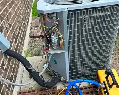 AC unit with open panel for repair, surrounded by tools and hoses.