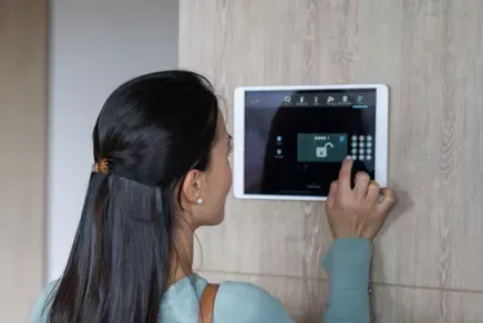 Person using a wall-mounted touchscreen security panel indoors