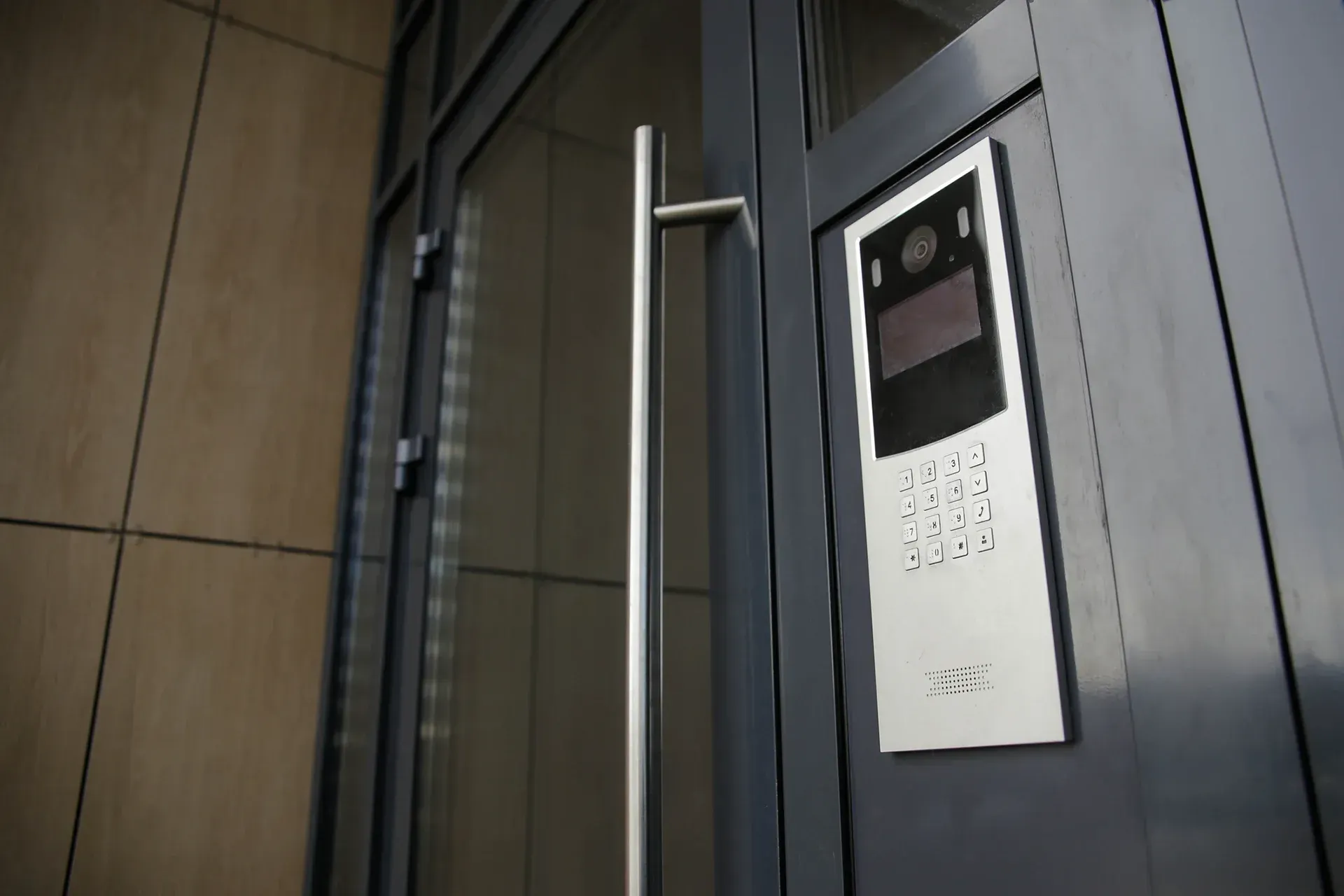 Close-up of a wall-mounted elevator control panel beside a closed door in a dark interior.