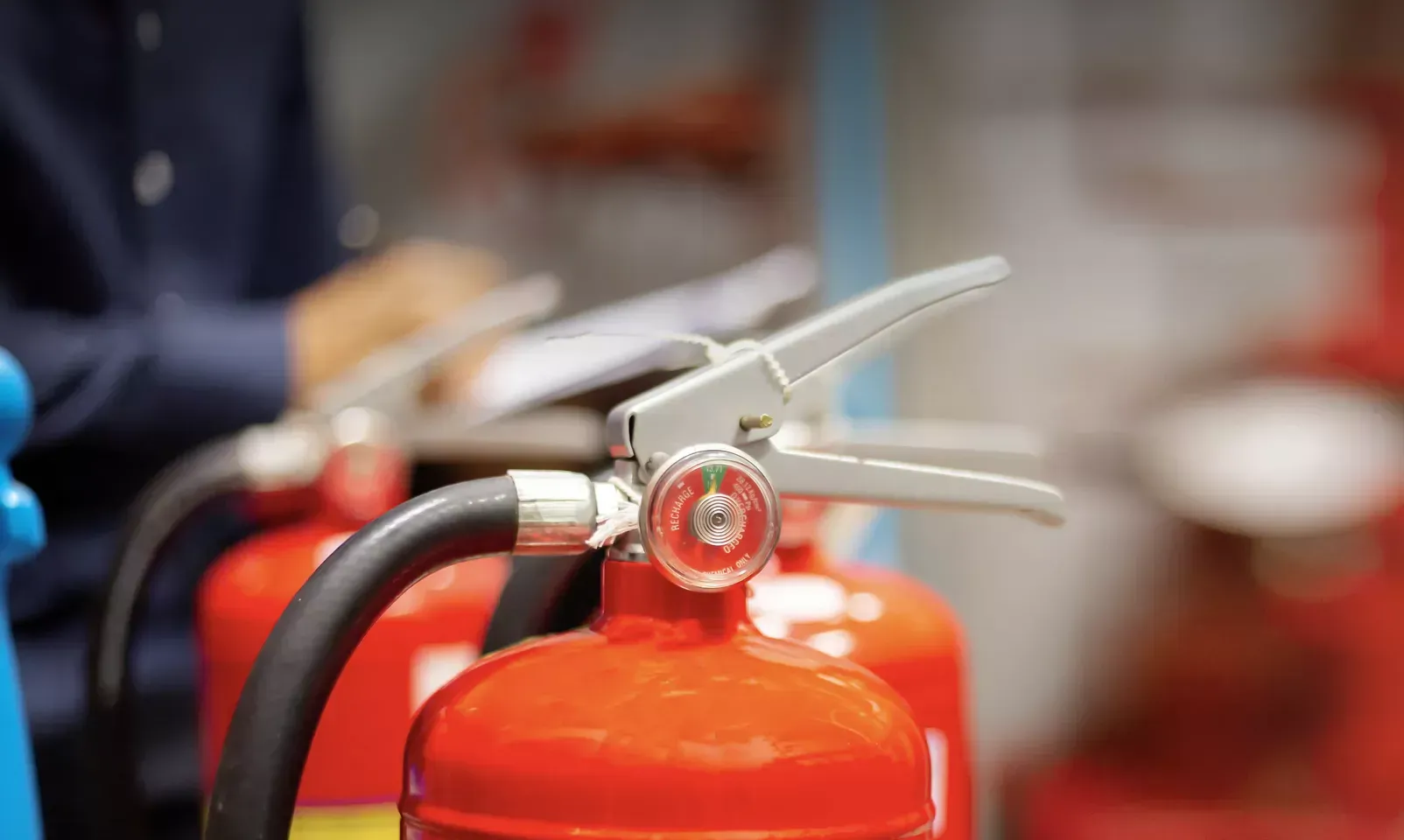 Close-up of a red fire extinguisher with metal nozzle and hose indoors