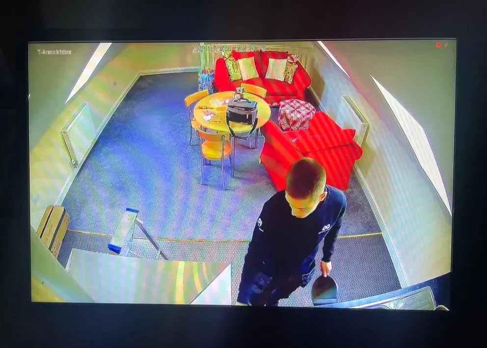 Overhead view of a room with red seating, a table, and a person walking in the foreground