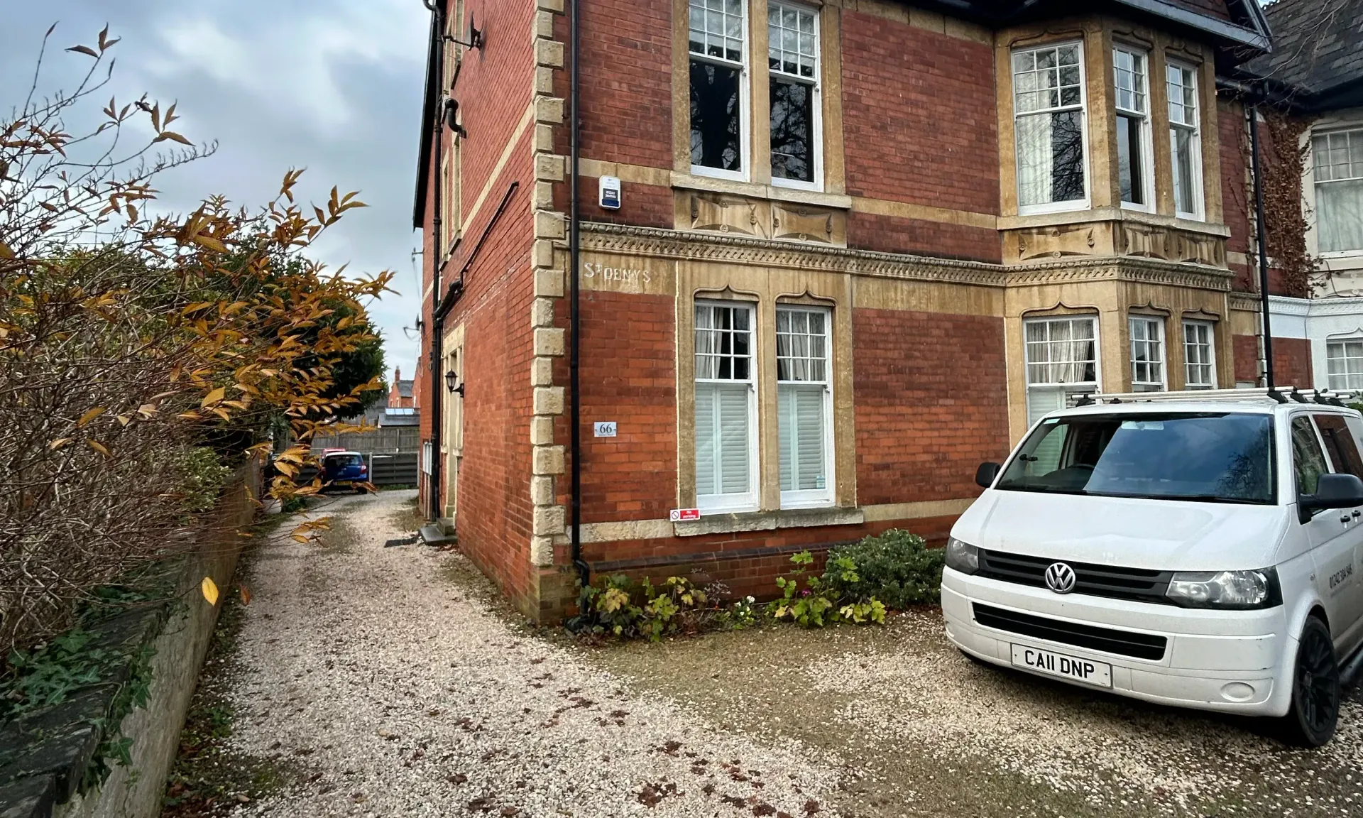 Brick house with gravel driveway and a white van parked outside in a residential area