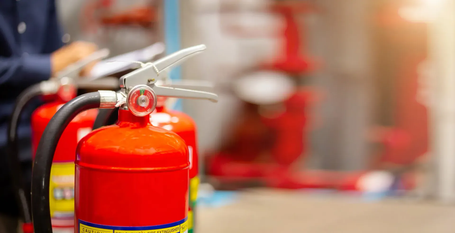 Red fire extinguisher with hose in a blurred indoor setting