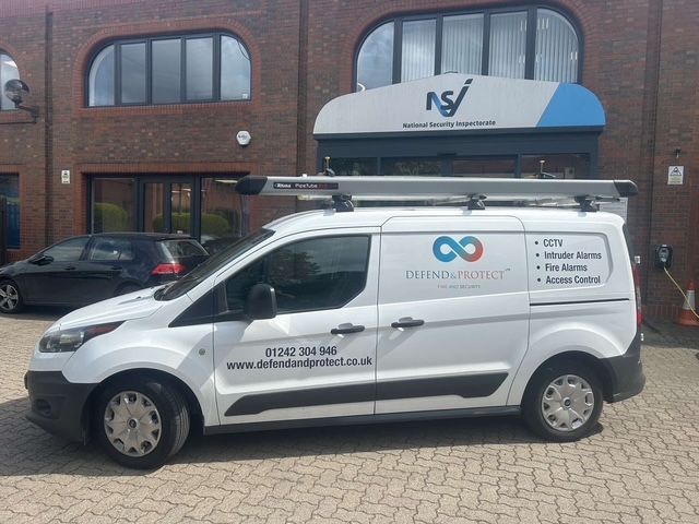 White service van parked outside a brick office building with NS sign above the entrance.